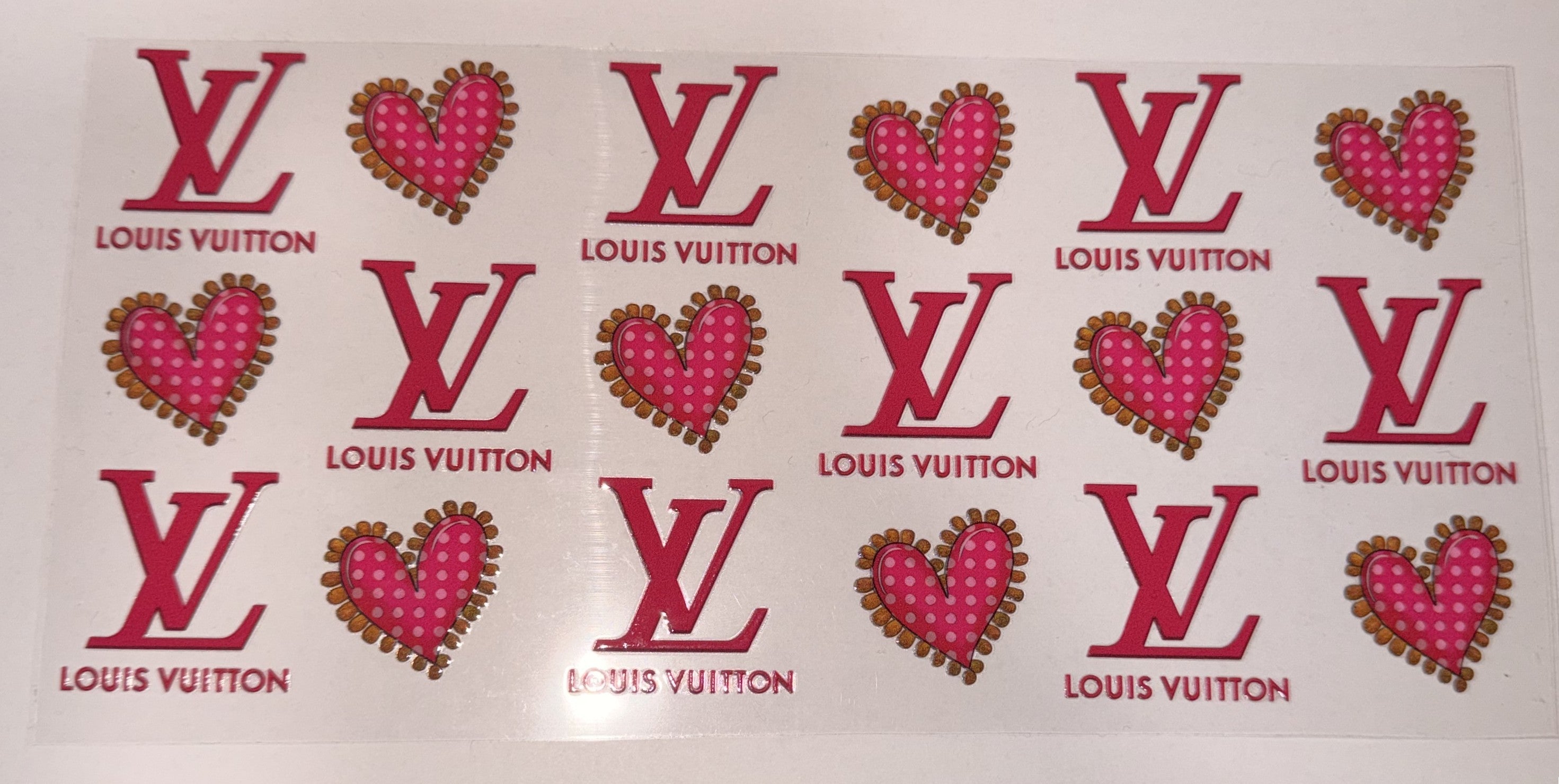 A sheet of Louis Vuitton rhinestone stickers featuring pink and red LV monogram logos and heart motifs with gold rhinestones on a white background.