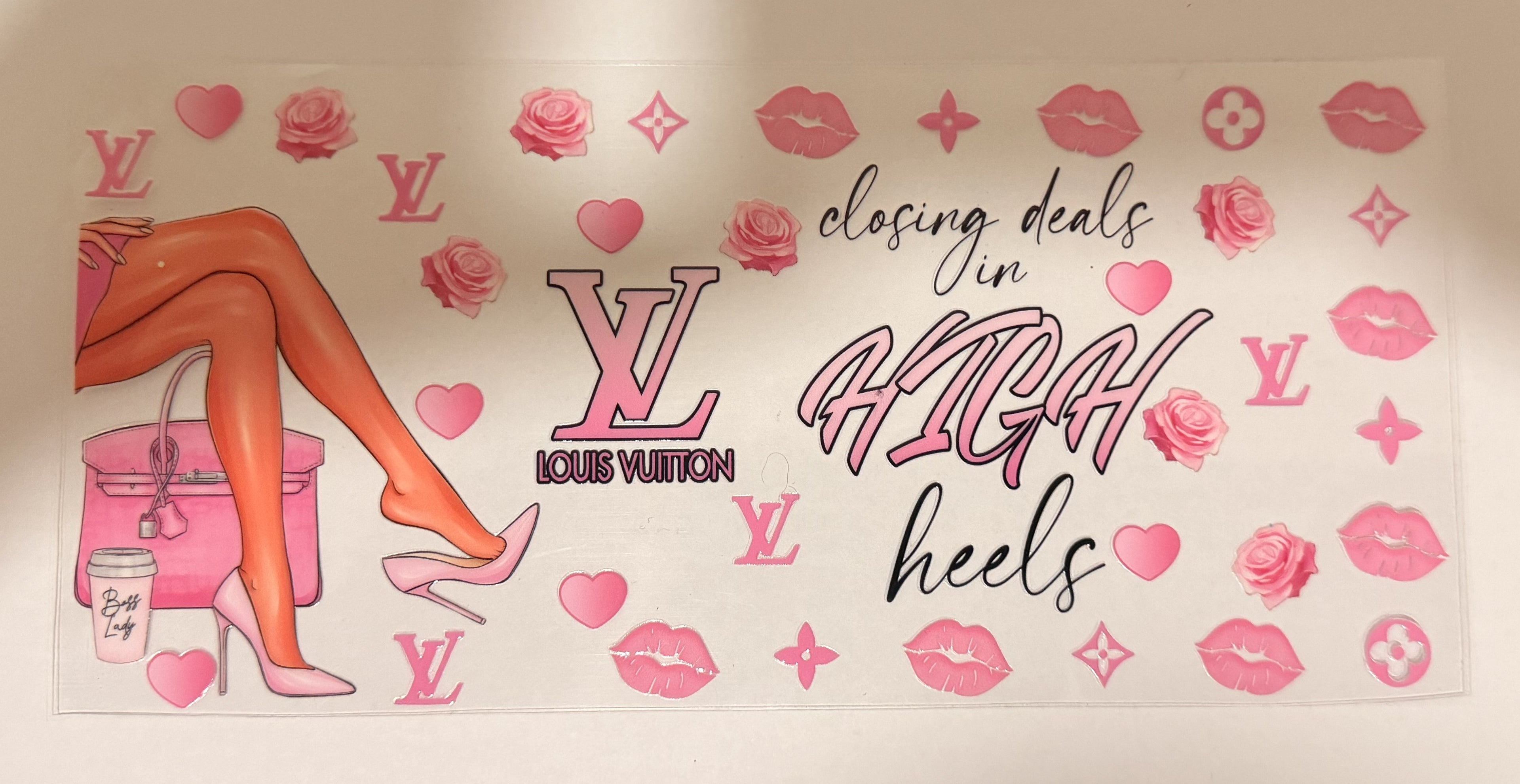 A rectangular wall decal or poster featuring pink Louis Vuitton-inspired monogram motifs, hearts, roses, lips, and a stylized illustration of legs in pink high heels beside a pink bag. The text reads 'closing deals in HIGH heels' with a large LV logo and 'LOUIS VUITTON' beneath it.