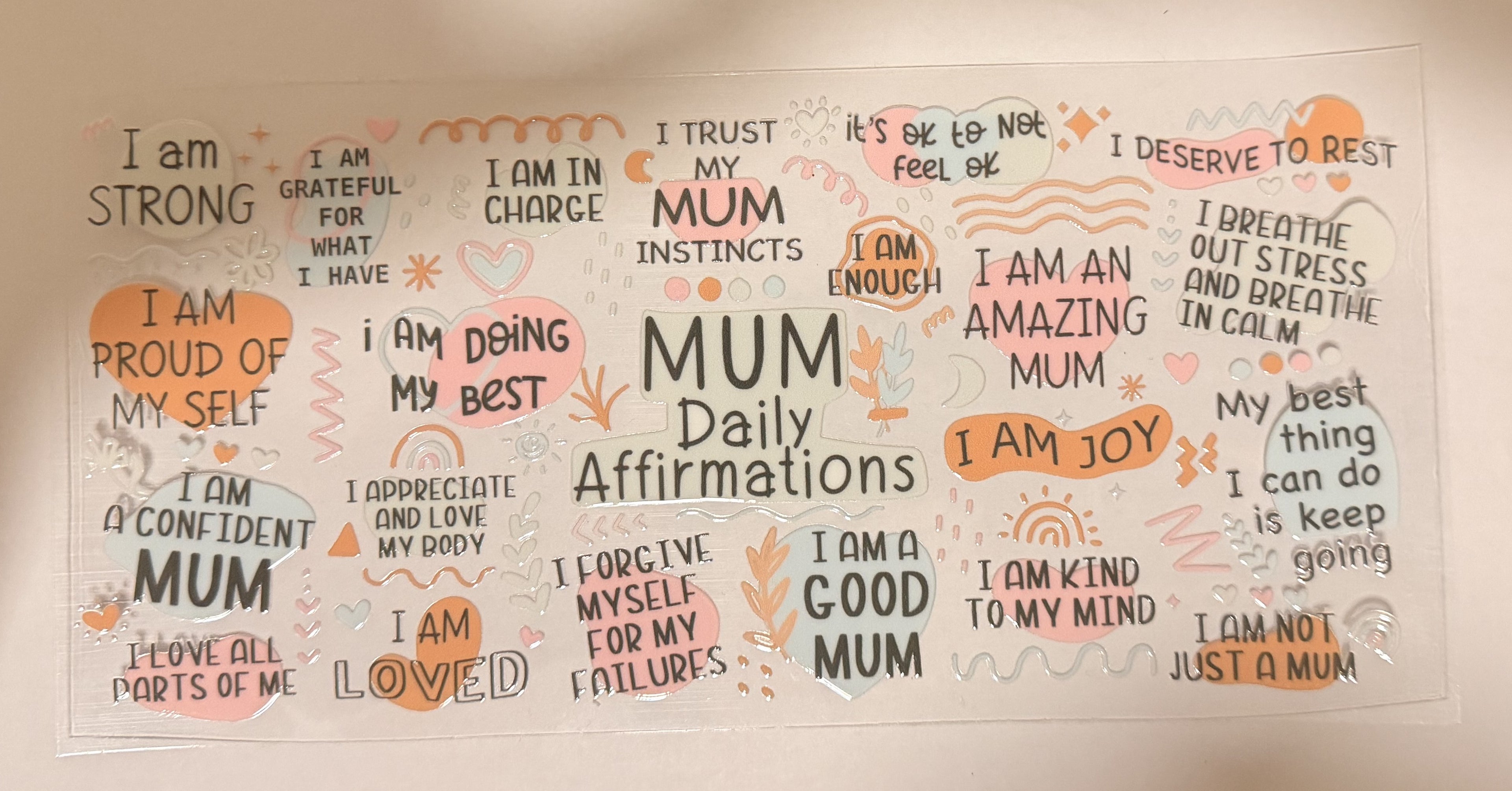 A rectangular white sticker sheet featuring various hand-drawn style orange and black affirmations for Mums, with the central text 'MUM Daily Affirmations'.