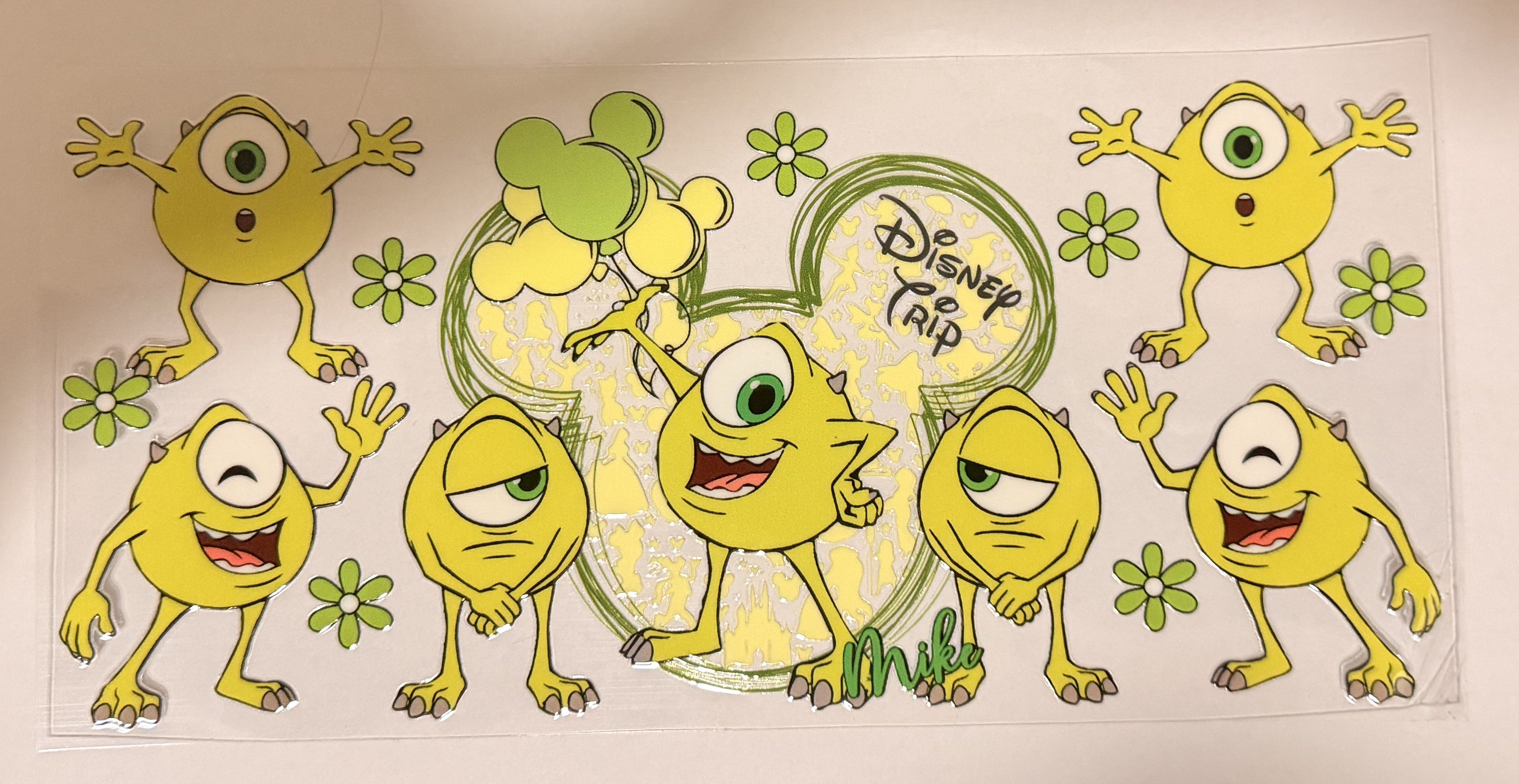 A Disney Trip Mickey Mouse-themed sticker sheet featuring multiple yellow cartoon characters inspired by Monsters, Inc., green flowers, and a large Mickey-shaped outline with the text 'Disney Trip' on a white background.